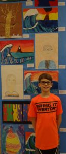 Student standing next to his artwork